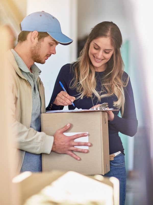 Shot of a delivery man making a delivery to a happy customer at her home.